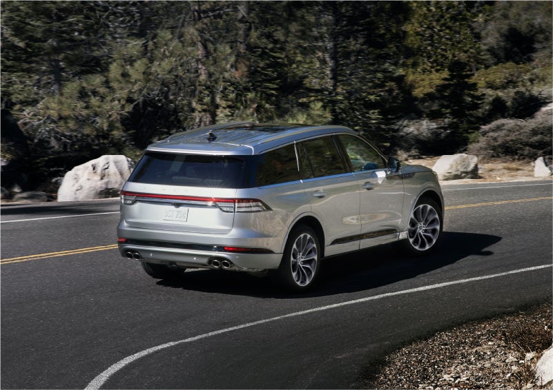 A 2023 Lincoln Aviator® Grand Touring model is shown being driven on a tight turn of a mountain road | Caruso Lincoln in Long Beach CA