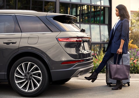 A woman with her hands full uses her foot to activate the hands-free liftgate. | Caruso Lincoln in Long Beach CA