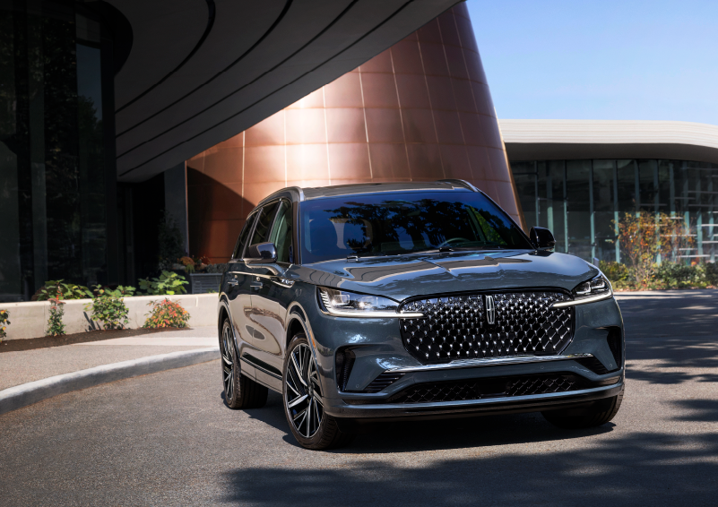A gray 2025 Lincoln Aviator® SUV is parked outside a modern building with the sun shining. | Caruso Lincoln in Long Beach CA