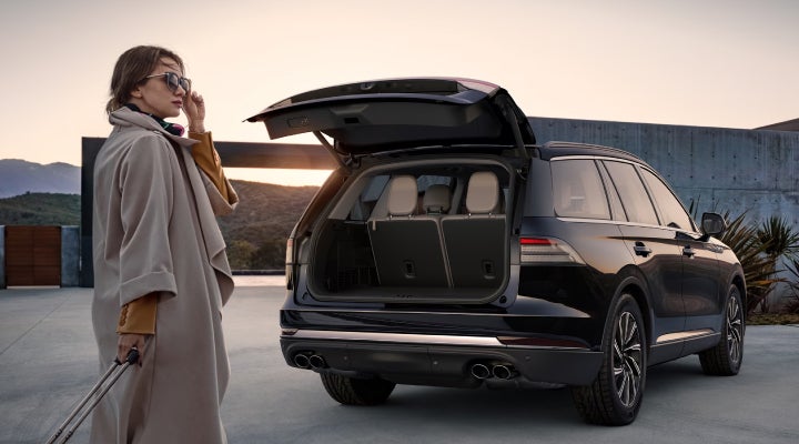 A woman approaches a 2026 Lincoln Aviator® SUV with its rear liftgate open. | Caruso Lincoln in Long Beach CA