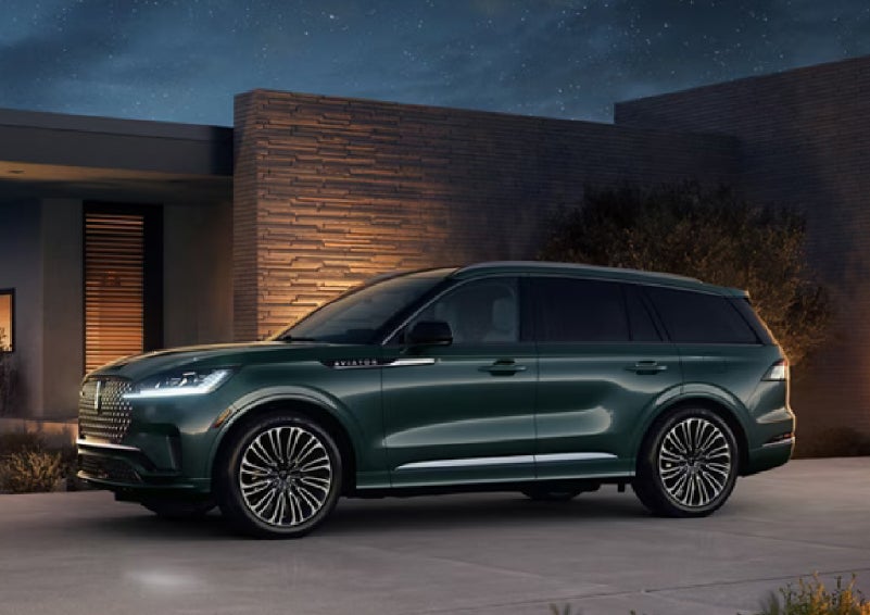 A green 2027 Lincoln Aviator® SUV is parked outside a contemporary home. | Caruso Lincoln in Long Beach CA