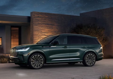 A green 2027 Lincoln Aviator® SUV is parked outside a contemporary home. | Caruso Lincoln in Long Beach CA