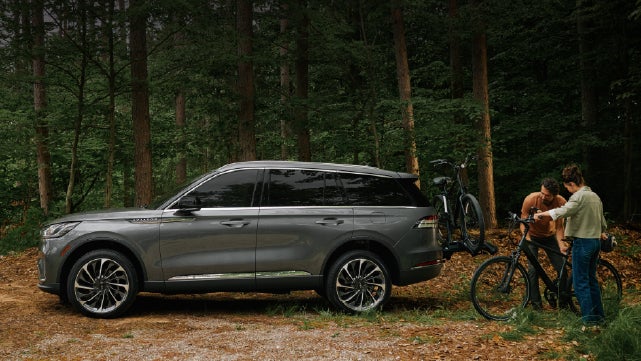 A father and son load e-bikes on a bike rack attached to a 2027 Lincoln Aviator® SUV. | Caruso Lincoln in Long Beach CA